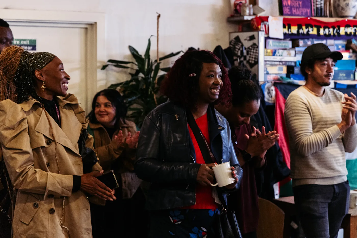 Guests smiling and applauding at the launch, one holding a white mug