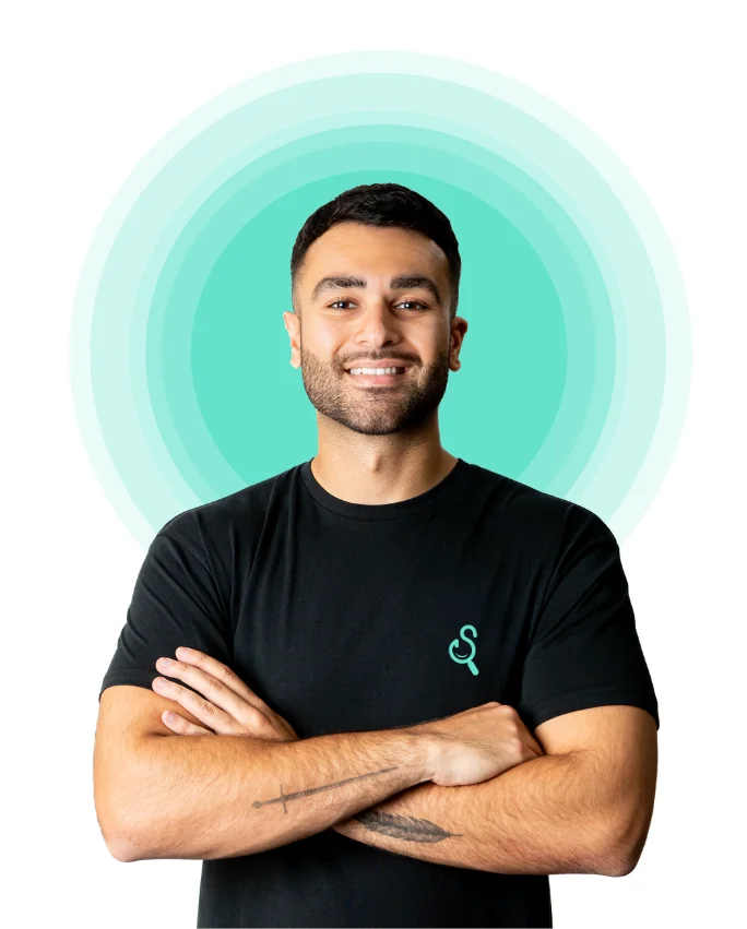 Louis Riat-Bonello, arms folded and smiling, in a black T-shirt in front of pale turquoise rings
